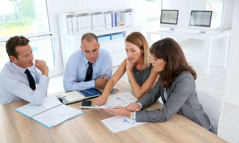 Group of business people meeting around table with tablet